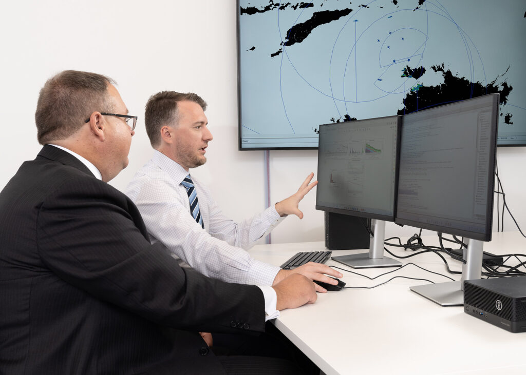 Two SPA Australia employees look at a computer together while one points at the computer screen graphs