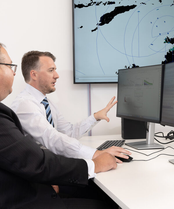 Two SPA Australia employees look at a computer together while one points at the computer screen graphs