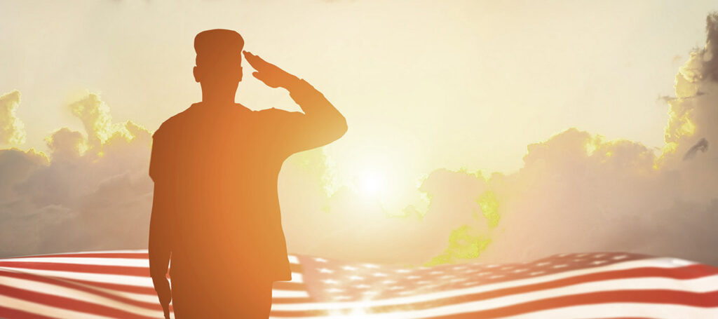 A stock image of a soldier saluting into the sunset. An American flag is overlaid in the image