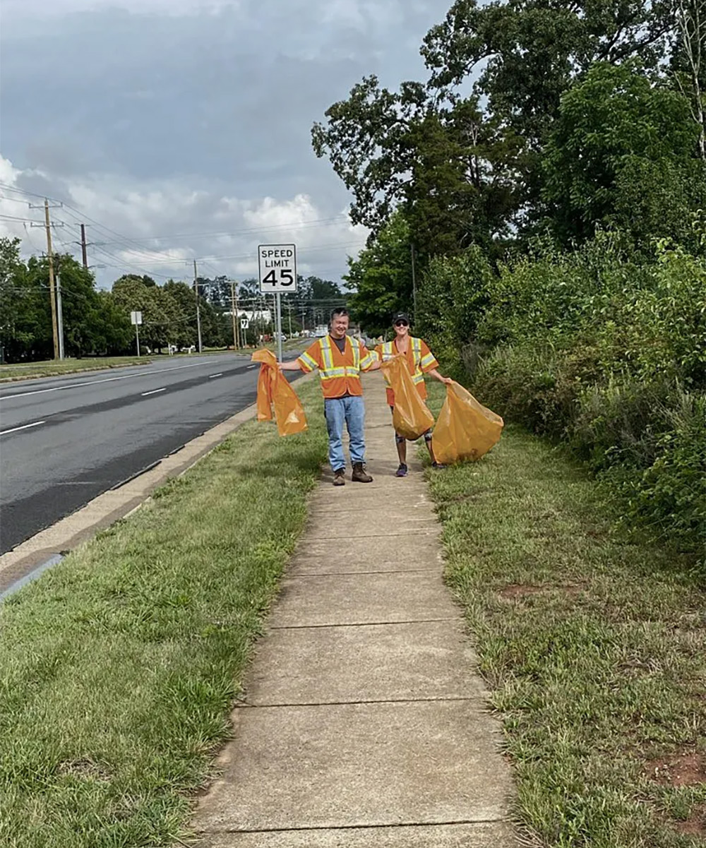 Two SPA employees pose while cleaning up the highway together in the community