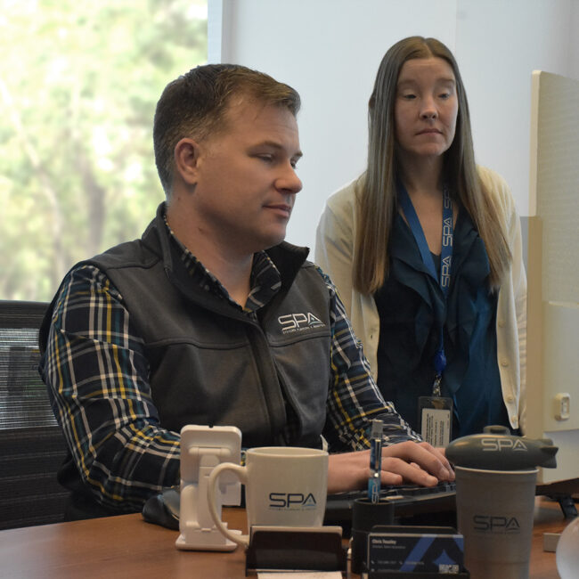 Employees on SPA's talent acquisition team review files on a computer at headquarters