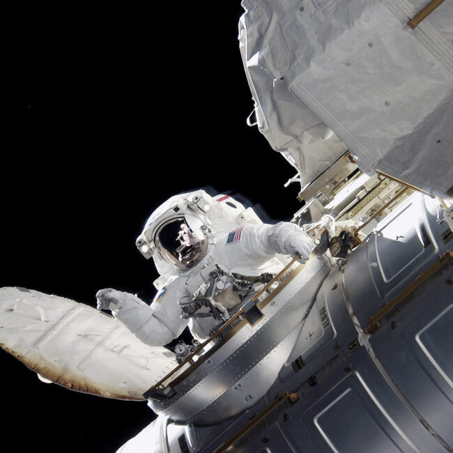 An astronaut enters the Quest Airlock on the International Space Station while Space Shuttle Atlantis was docked with the station.