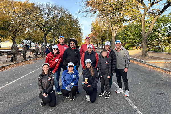 Systems Planning & Analysis employees pose together before volunteering to hand out water at the annual Marine Corps Marathon