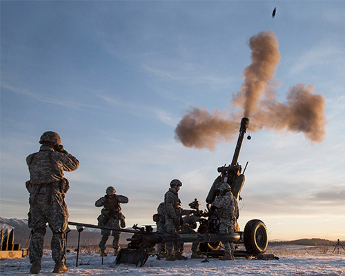 A photo showing US Army soldiers plugging their ears as missiles are fired from a snowy terrain