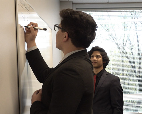 SPA employees meet and work through a problem together on a white board