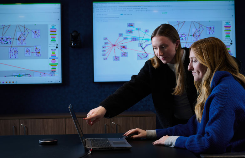 Two SPA employees review a laptop screen, pointing and discerning data presented, depicting SPA's dedication to technology