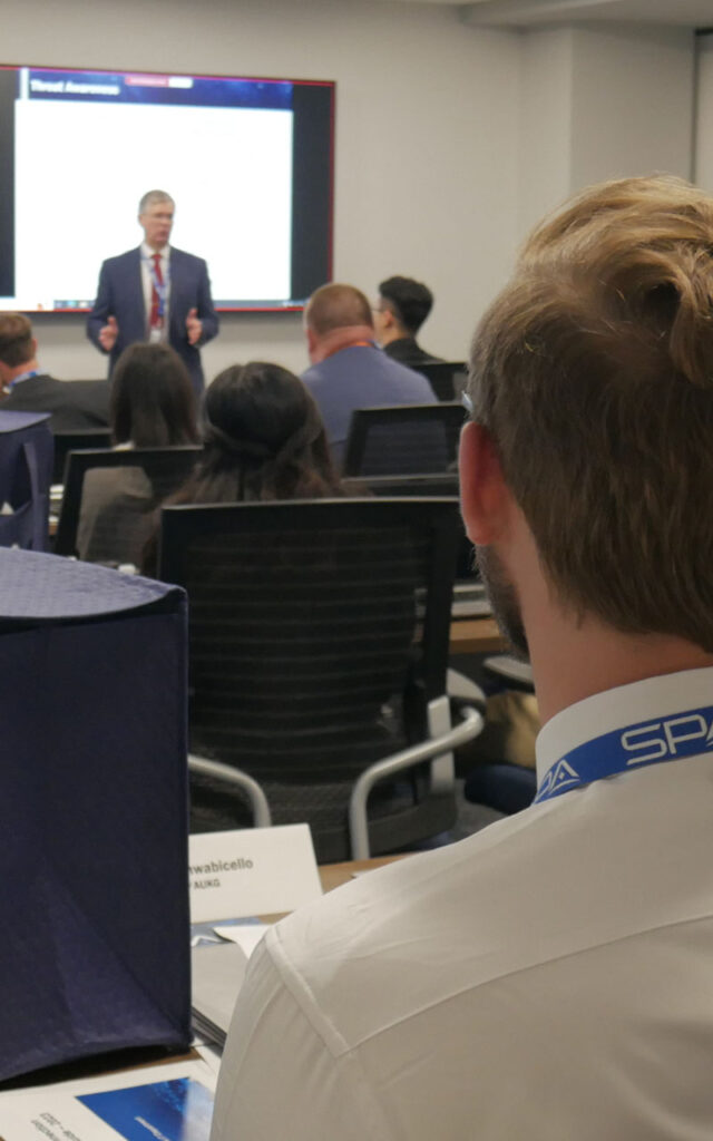 SPA employees sit in a large meeting room listening to a speaker