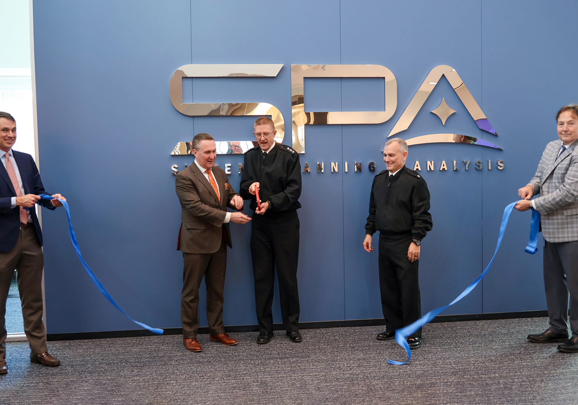 Systems Planning and Analysis (SPA) CEO Rich Sawchak and Director of Strategic Systems Programs (SSP) VADM Johnny Wolfe Jr. lead the ribbon-cutting ceremony for the new Maritime Plaza Collaboration Space. Joining them was Deputy Director, Regional Strike Systems, Strategic Systems Programs RDML Michael Richman (center-right), along with SPA CFO Dan Muse (far left) and SPA VP of Operations Chris Neubauer (far right). The new space is dedicated to advancing SLCM-N collaboration.