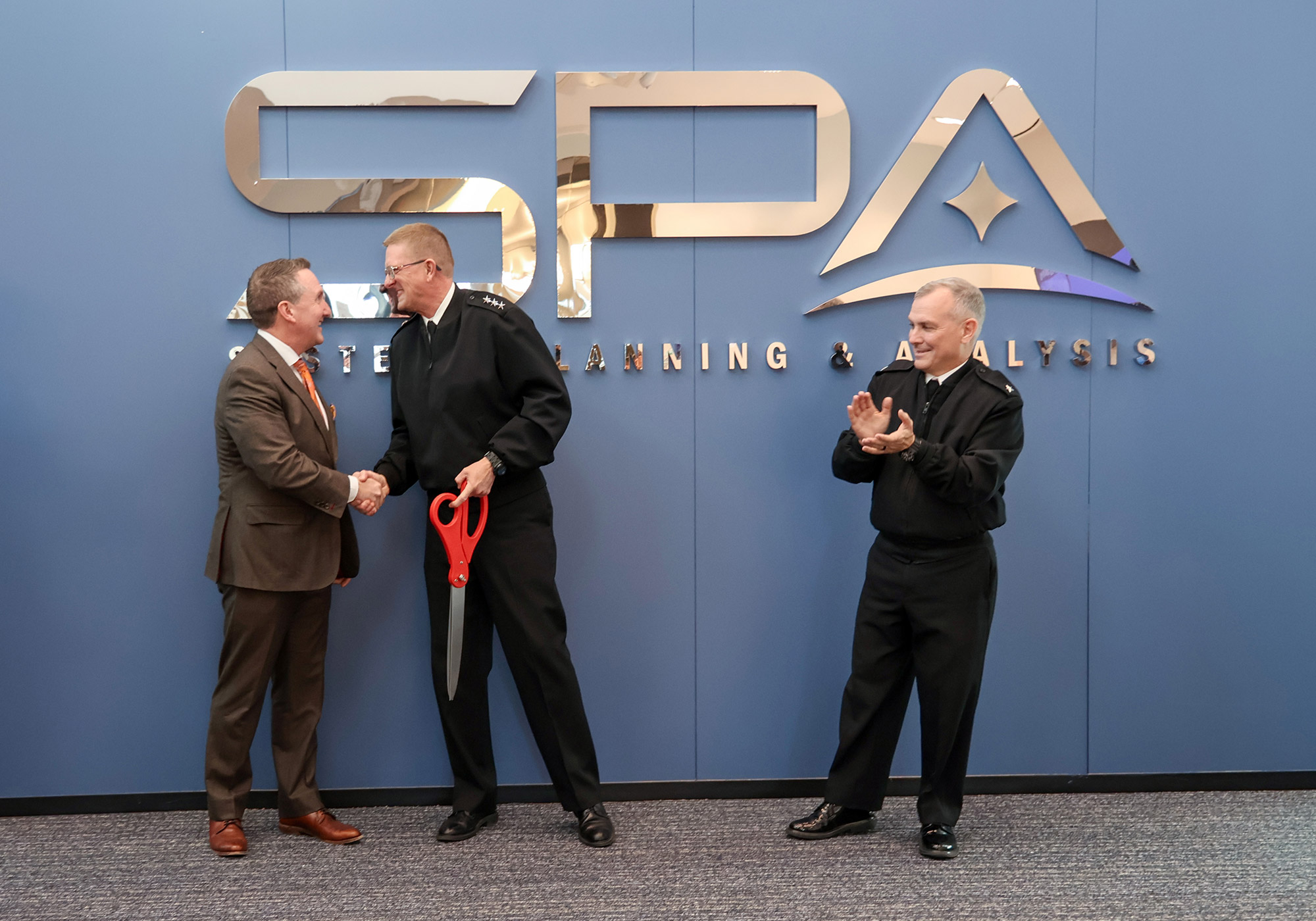 Systems Planning and Analysis (SPA) CEO Rich Sawchak and Director of Strategic Systems Programs (SSP) VADM Johnny Wolfe Jr. lead the ribbon-cutting ceremony for the new Maritime Plaza Collaboration Space. Joining them was Deputy Director, Regional Strike Systems, Strategic Systems Programs RDML Michael Richman (center-right), along with SPA CFO Dan Muse (far left) and SPA VP of Operations Chris Neubauer (far right). The new space is dedicated to advancing SLCM-N collaboration.